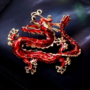 Chinese dragon brooch with red enamel and gold trim on black textured fabric