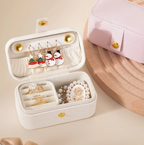 Mini travel jewelry box showing ring slots and earring hooks in white and pink PU leather
