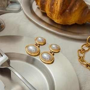 Golden double oval pearl earrings shown in a vintage French style lifestyle setting