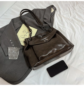 Dettaglio della borsa tote color caffè con trama a grana e chiusura a scatto in metallo