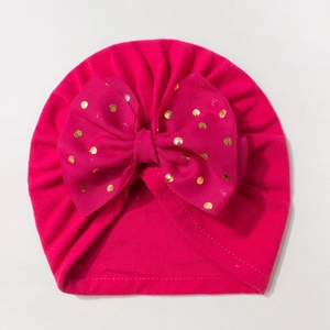 Detail of rose red baby turban with large bow and golden polka dots pattern