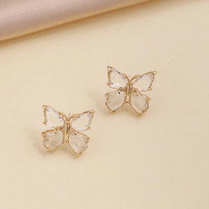 Detail of gold butterfly earrings set with clear zircon stones on golden silk fabric