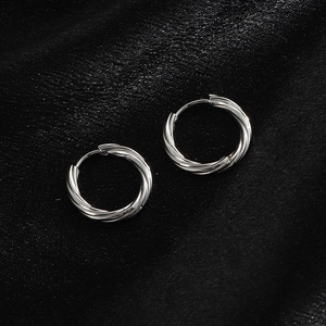 Macro detail of silver twisted hoop earrings with textured finish on black silk