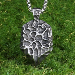 Oxidized steel Evil Eye pendant necklace with hammered texture and box chain on grass