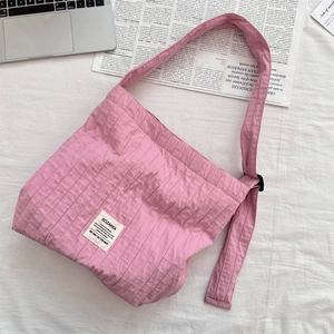 Close-up of pink pleated tote bag with canvas texture and adjustable black buckle strap