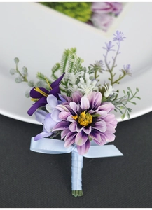 Detail of a handmade purple dahlia boutonniere with green fern and blue ribbon bow