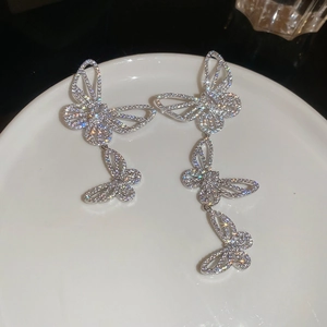 Macro shot of silver butterfly drop earrings with sparkling cubic zirconia on ceramic