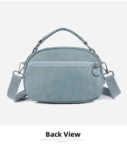 Rear view of a light blue nylon crossbody bag with wide shoulder strap and silver zipper