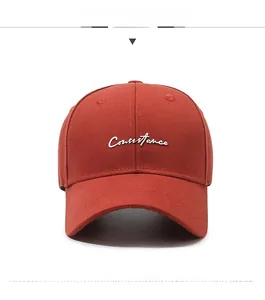 Front view of a brick red baseball cap with white Constance embroidery on twill fabric