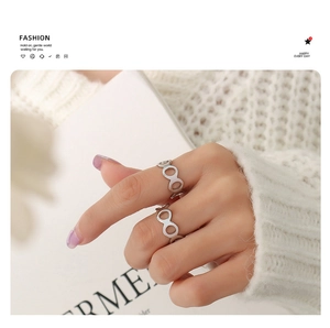 Detailed close-up of a silver hollow geometric ring worn with a white sweater