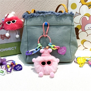 Porte-clés monstre en peluche rose avec étiquette cœur sur une poche de sac à dos