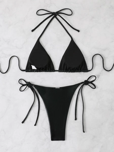 Flat lay of a sexy black metallic bikini set with tie-up straps on white marble