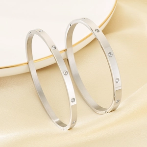 Pair of minimalist silver stainless steel round bangles with zircon inlay on silk background