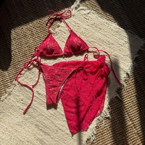 Detail shot of red lace three-piece bikini set with sheer mesh skirt and halter neck design