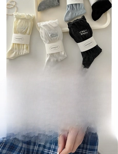 Detail of grey knitted socks with ruffles and ribbons arranged in a cream tray