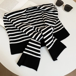 Flat lay of a classic black and white striped knit shawl with sunglasses and a magazine