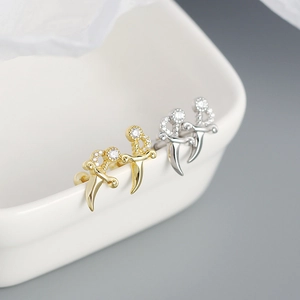 Macro view of gold and silver dagger stud earrings with sparkling crystal accents