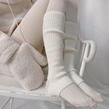 Close-up of white ribbed knit leg warmers and matching gloves on a white chair