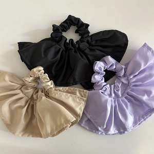 Three satin scrunchies in black, beige, and lilac with double-layered ruffled edges