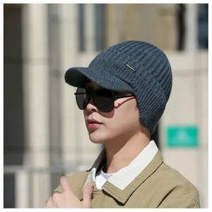 Dettaglio cappello invernale in maglia grigio scuro con paraorecchie e logo in metallo