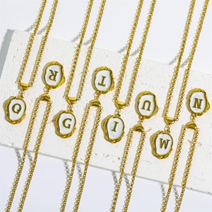 Detail of 18K gold plated popcorn chains with white enamel letter pendants on a display
