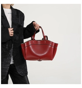 Dettaglio borsa tote bordeaux con design alato, cuciture laterali e texture in pelle