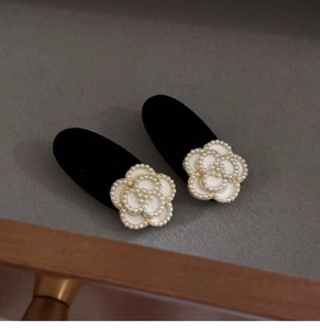 Macro view of velvet hair clips with enamel camellia flower and pearl inlay detailing