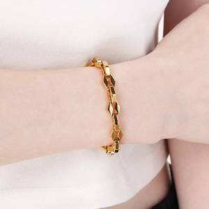 Détail d'un bracelet gourmette géométrique en or 18 carats poli porté au poignet