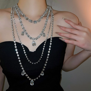 Detail of layered silver tassel necklace featuring sparkling square and round crystals