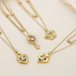 Close-up of four gold heart pendants with crystals on a textured stone display