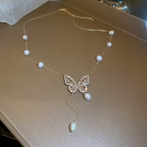 Detail of gold plated butterfly pendant necklace with freshwater pearls and zircon stones