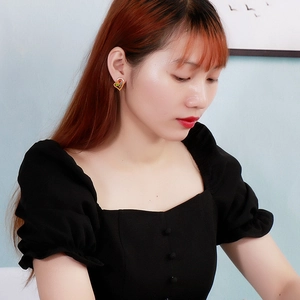 Élégantes boucles d'oreilles cœur dorées avec dégradé coloré portées par un mannequin