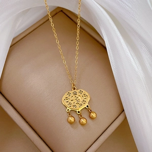 Macro detail of a gold Ruyi lock pendant with bells on a silk jewelry cushion