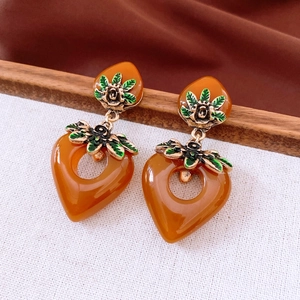 Detail of vintage heart earrings with gold rose floral relief and caramel resin