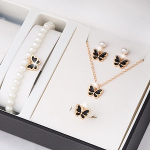 Parure de bijoux papillon en émail noir avec perles présentée dans une boîte cadeau