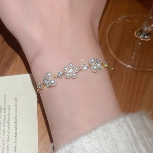 Detailed close-up of a luxury gold flower pearl bracelet on a woman's wrist