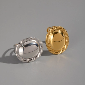 Close-up of gold and silver oval rings with intricate lace-edged textures on neutral background