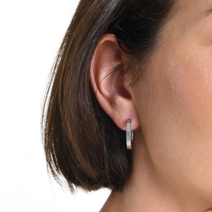 Close-up of polished silver stainless steel hoop earring shown on model ear