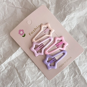 Close-up of four colorful star-shaped hair clips in pink, purple and beige colors