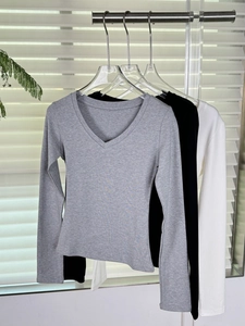 Détail de t-shirts à manches longues et col en V en gris, noir et blanc sur cintres