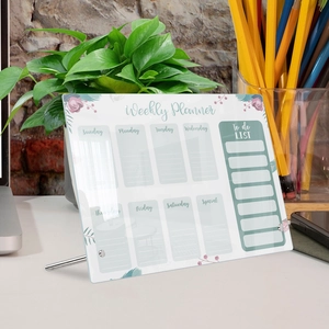 Detailed acrylic weekly planner with green floral patterns on an office desk
