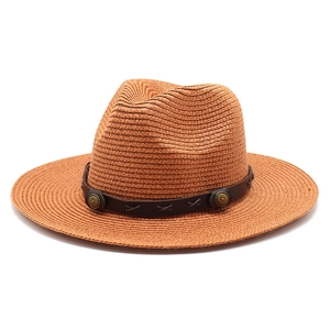 Détail d'un chapeau de paille beige avec bandeau en cuir et rivets métalliques