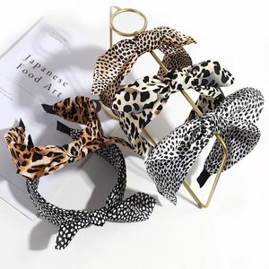 Detail view of four leopard print bow headbands in various colors on a white tabletop