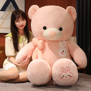 Detail of pink teddy bear with white rabbit embroidery and decorative bow on plush chest