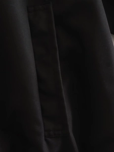 Detailed close-up of the black twill fabric and reinforced stitching on a bomber jacket