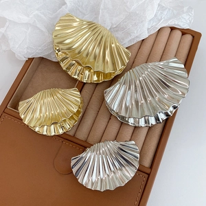 Detailed view of polished metal scallop hair claws in gold and silver finishes