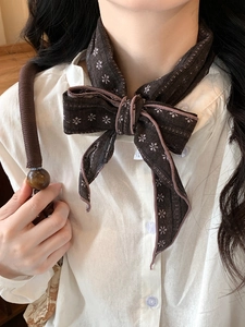 Close-up of a vintage dark brown striped floral neckerchief tied in a bow over white shirt