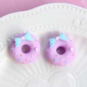 Macro view of purple resin donut charms with blue bows and colorful sprinkles for DIY
