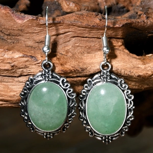 Macro detail of vintage silver oval green stone earrings on a rustic wood texture