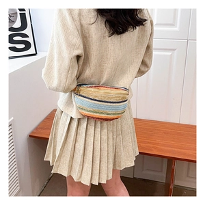 Colorful striped straw waist bag with golden zipper worn across the back on model